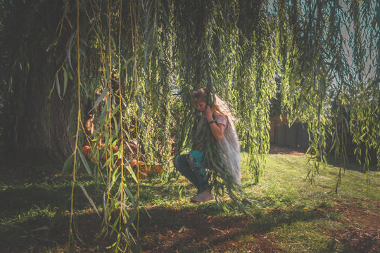 little child portrait in green spring nature by the tree willow with long green limbs - Powered by Adobe