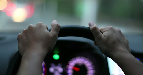 Driver POV hands holding steering wheel waiting. Person hand close-up point of view in red light