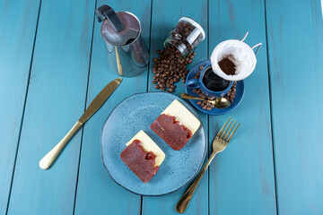 Guava sweet with cheese surrounded by cutlery, cup and coffee beans on a blue table_top view.