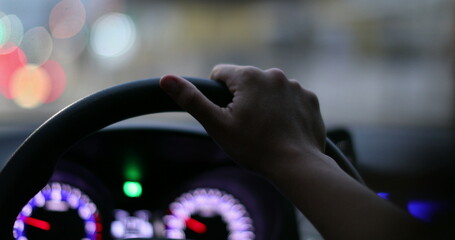 Close-up hands holding car steering wheel driving at night in city