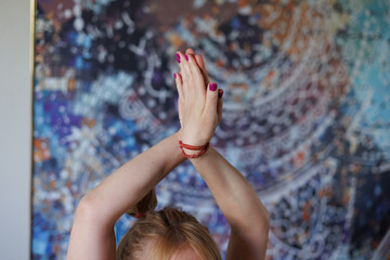 Fototapeta premium Closeup of woman hands in yoga pose. Woman hands doing pilates exercises. Beautiful palm with pink manicure. Flexible blond girl doing yoga poses indoors 