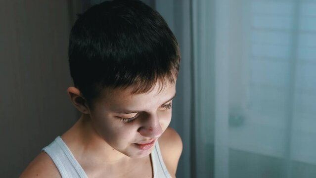 Face of a Guilty, Speaking Smiling Teenager with a Downcast Look. Side view. Conflict with parents, repentance, punishment, awareness of guilt. Behavior, emotion, reaction, dialogue. Childhood age.