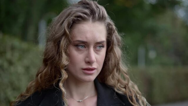 Close-up face of worried young woman with anxious facial expression looking around standing outdoors. Beautiful Caucasian stressed lady with panic attack in park. Mental problem concept