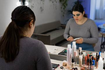 close-up rear-view photo of a woman in front of a mirror during a make-up process