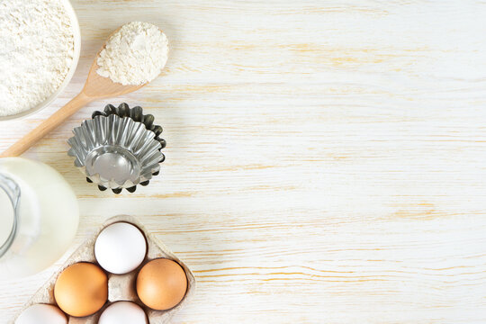 Baking cooking Ingredients background with copy space. Flour, eggs, milk, bakeware on white wooden surface. Top view, flat lay. Mockup menu, banner, header for site, baking concept