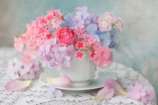 Colorful bouquet with hydrangea, rose and phlox in a cup on the table. Greeting card for the holidays.