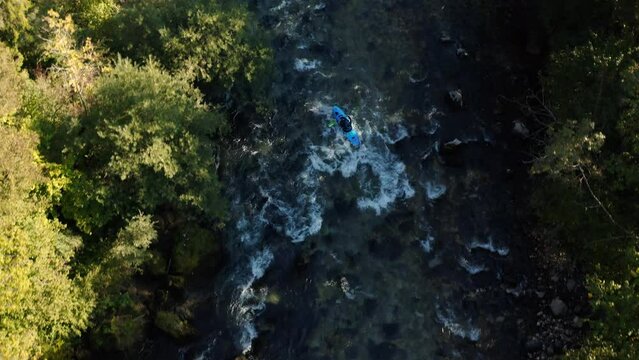 Kayaker paddling down a series of river rapids. Aerial view, drone shot.