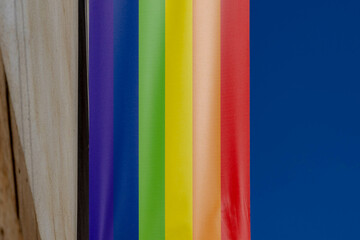 Celebration of Pride month concept, Colourful rainbow flag hanging outside building with blue sky,...