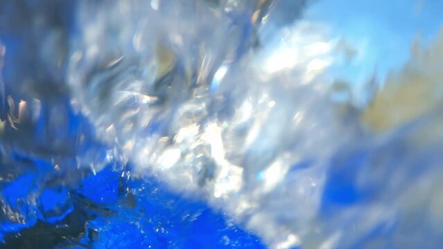 Front view of a young Caucasian whitewater kayaker paddling down a turbulent river, water splashes the camera, close up shot.