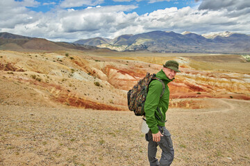 man tourist traveler in jacket stands against backdrop of landscape on summer day. Sights of Russia, Siberia and Altai Republic, mars field. Tourism, travel and adventure. Kosh-agach, Chagan-Uzun