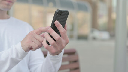 Close Up of Young Man Using Smartphone while Sitting Outdoor on Bench