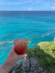 person drinking Bloody Mary cocktail by the ocean