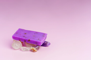 A piece of homemade lavender soap lies on decorative stones
