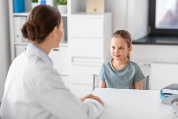 medicine, healthcare and pediatry concept - female doctor or pediatrician talking to little girl patient on medical exam at clinic