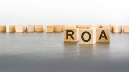 Obraz premium text ROA on wooden cubes on gray background. abbreviation of 'Return on Assets'. square wood blocks. top view, flat lay.