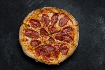Pizza with sausage and spices on gray concrete