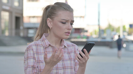 Upset Young Woman Reacting to Loss on Smartphone Outdoor