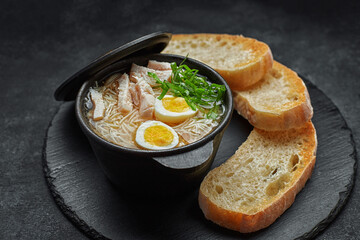 Chicken broth with egg and croutons in a pot