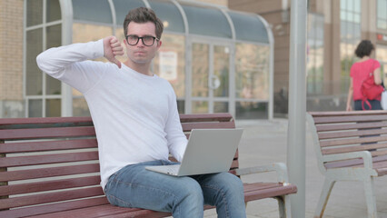 Thumbs Down by Young Man with Laptop Sitting on Bench