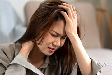 Female employee sitting on the floor to touching forehead and the neck while feeling stressed and disappointed