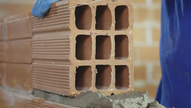 Pedreiro assentando tijolos com cimento em obra. Constru&ccedil;&atilde;o de casa ou pr&eacute;dio.