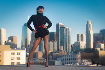 Glamorous tattooed woman in fishnet stockings and high heels poses on a Downtown Los Angeles Rooftop