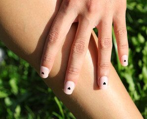 girls hand with nails with black heart symbol and pale pink nail polish