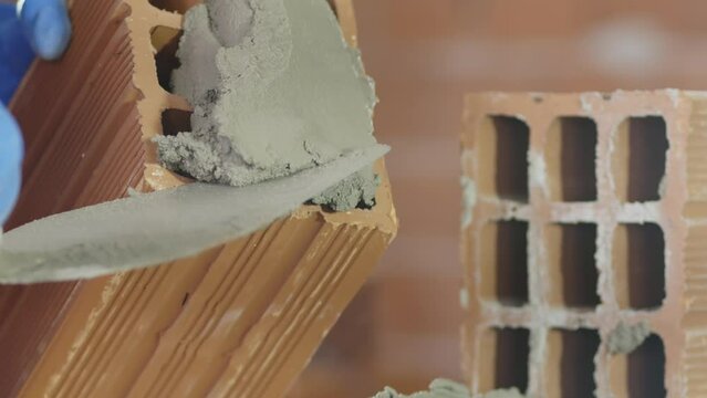 Pedreiro assentando tijolos com cimento em obra. Constru&ccedil;&atilde;o de casa ou pr&eacute;dio.