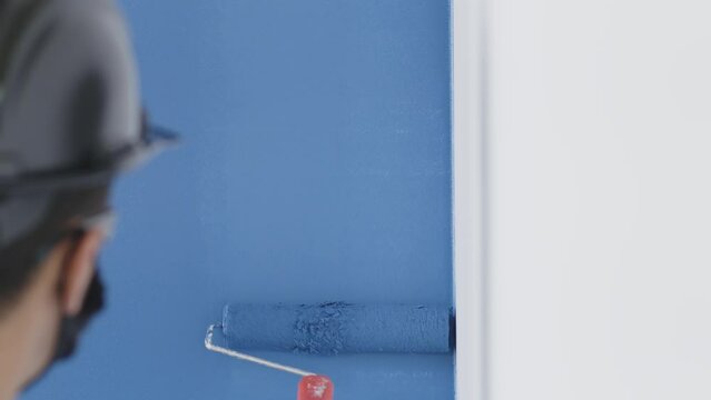 Parede branca sendo pintada de azul com rolo de pintura. 