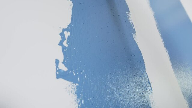 Parede branca sendo pintada de azul com rolo de pintura. 