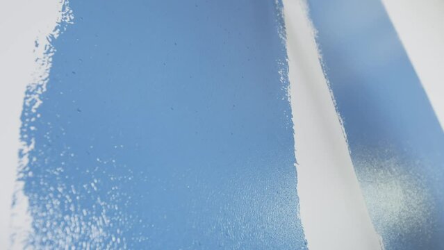 Parede branca sendo pintada de azul com rolo de pintura. 