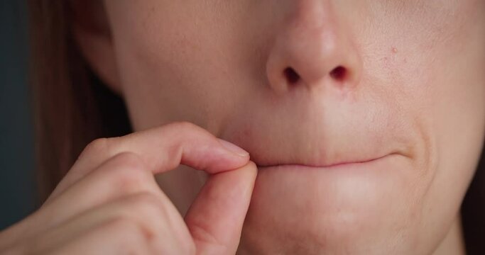 Woman, showing the zipped lips gesture, close-up mouth