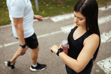 Young woman checking progress on smart watch. Female runner looking at smart watch heart rate monitor
