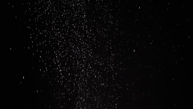 Stream of Slowly Falling Particles of Dust, Debris, Powder on Black Background. Sparks, particles of white powder, flakes rotate, swirl, float in cloud fog. Empty space. Star rain, meteorites. Cosmos.