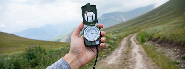 Man with compass in hand on mountains road © ARAMYAN