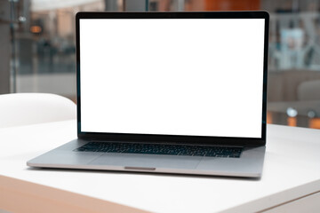 Laptop with white screen in business office or shopping mall. Empty copy space, blank screen mockup. Soft focus laptop with interor background. Travel, study and office work concept
