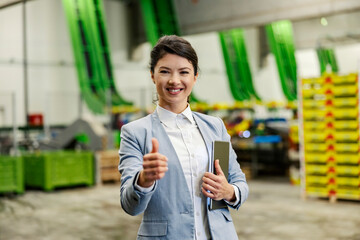 Portrait of a businesswoman giving thumbs up and smiling at the camera.