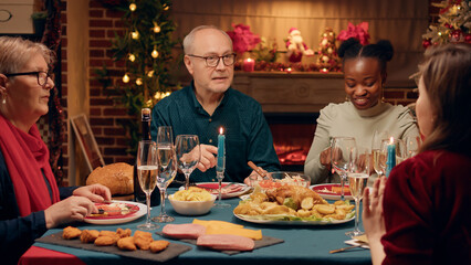 Fototapeta na wymiar Senior person talking praising daughter about traditional home cooked food at Christmas dinner table. Festive family members celebrating winter season holiday while enjoying time together at home.