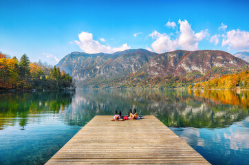 Fabulous view  of  Bohinj Lake with couple lying on a wooden pier