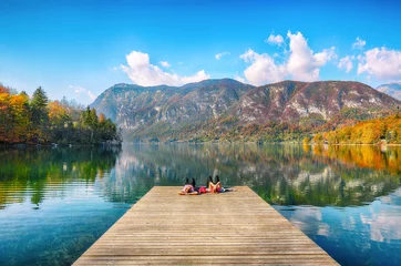 Schilderijen op glas Fabulous view  of  Bohinj Lake with couple lying on a wooden pier © pilat666