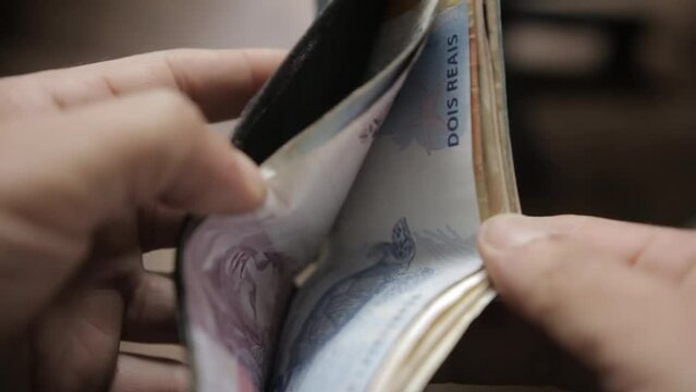 A man check his wallet for some Brazilian Real bills and notes