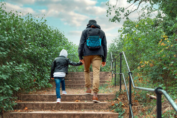 man holding a child's hand climb up the steep stairs