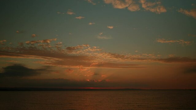 Seascape with beautiful sunset and clouds in the sky. Time lapse of majestic sunset landscape. Amazing nature light of cloudy sky and clouds receding from rolling colorful sunset dark clouds 