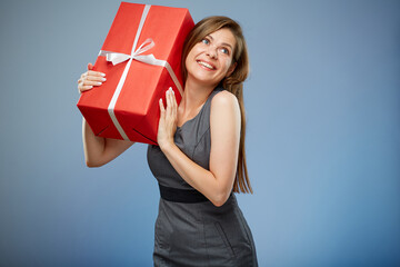 Happy woman holding red gift box on shoulder, looking up, isolated portrait.