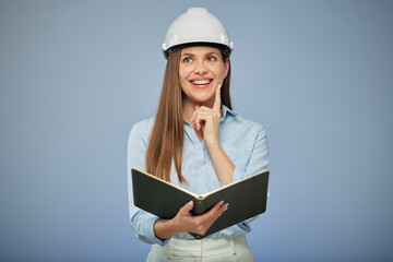 Thinking woman engineer in protective industrial helmet holding book. Isolated female portrait.