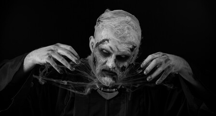 Sinister man with horrible scary Halloween zombie makeup in costume making faces, looking ominous...