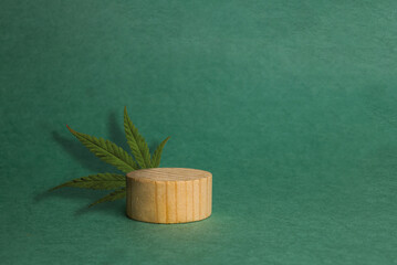 brown precious wood box, block, cylindrical podium, cannabis leaf on a green background. concept...