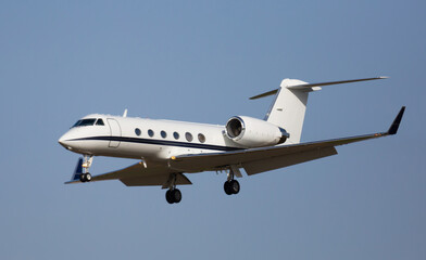 Modern comfortable private jet flying in blue sky, approaching landing ..
