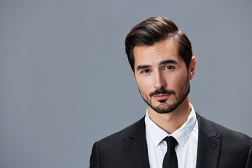 Portrait of a business man in a stylish suit with tie beautiful face on a gray isolated background. Business concept young businessman startup copy space