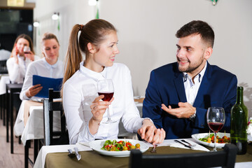 Gentleman with elegant woman are having dinner in luxury restaurante indoor.